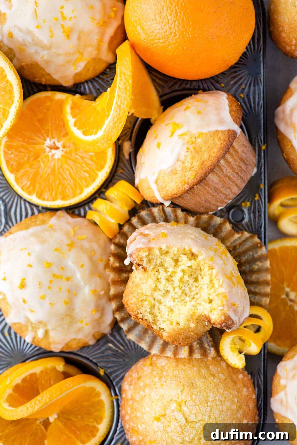 A vibrant display of freshly baked orange muffins arranged in an appealing grid pattern, accompanied by cheerful slices of fresh oranges, embodying the delicious citrus theme.