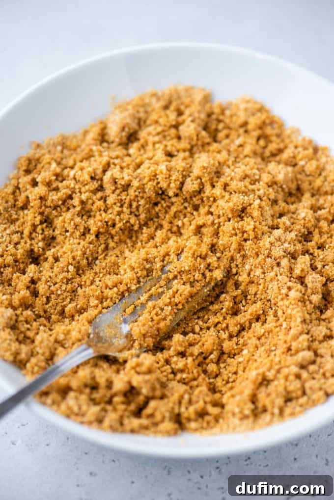 Graham cracker and butter mixture resembling wet sand, ready for pressing.