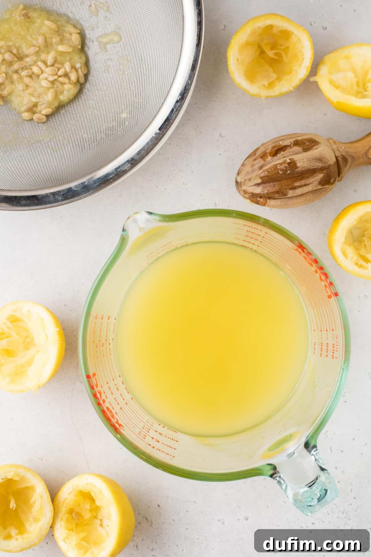 An overhead view of a clear glass measuring cup filled with approximately 1 1/2 cups of freshly squeezed lemon juice.