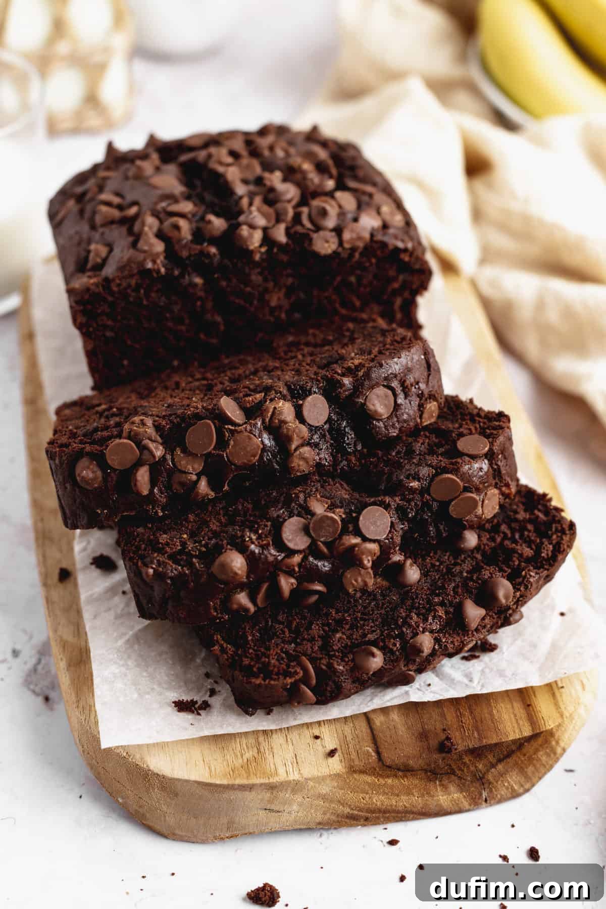 A beautifully sliced loaf of Double Chocolate Banana Bread on a wooden cutting board, ready to be enjoyed with its rich color and visible chocolate chunks.