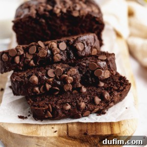Three slices of chocolate banana bread on wooden cutting board