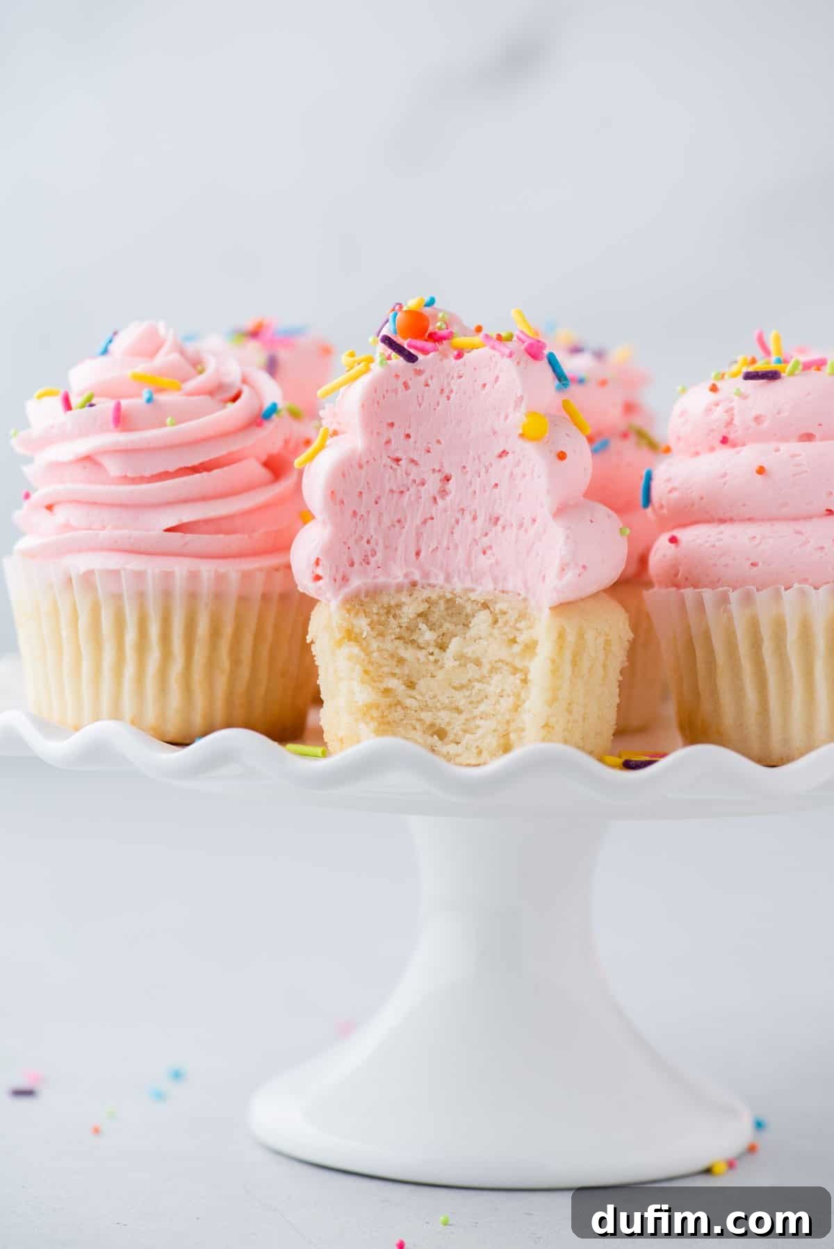 A freshly baked gluten-free cupcake, cut open to reveal its perfectly light and fluffy texture, invitingly placed on a cake stand.
