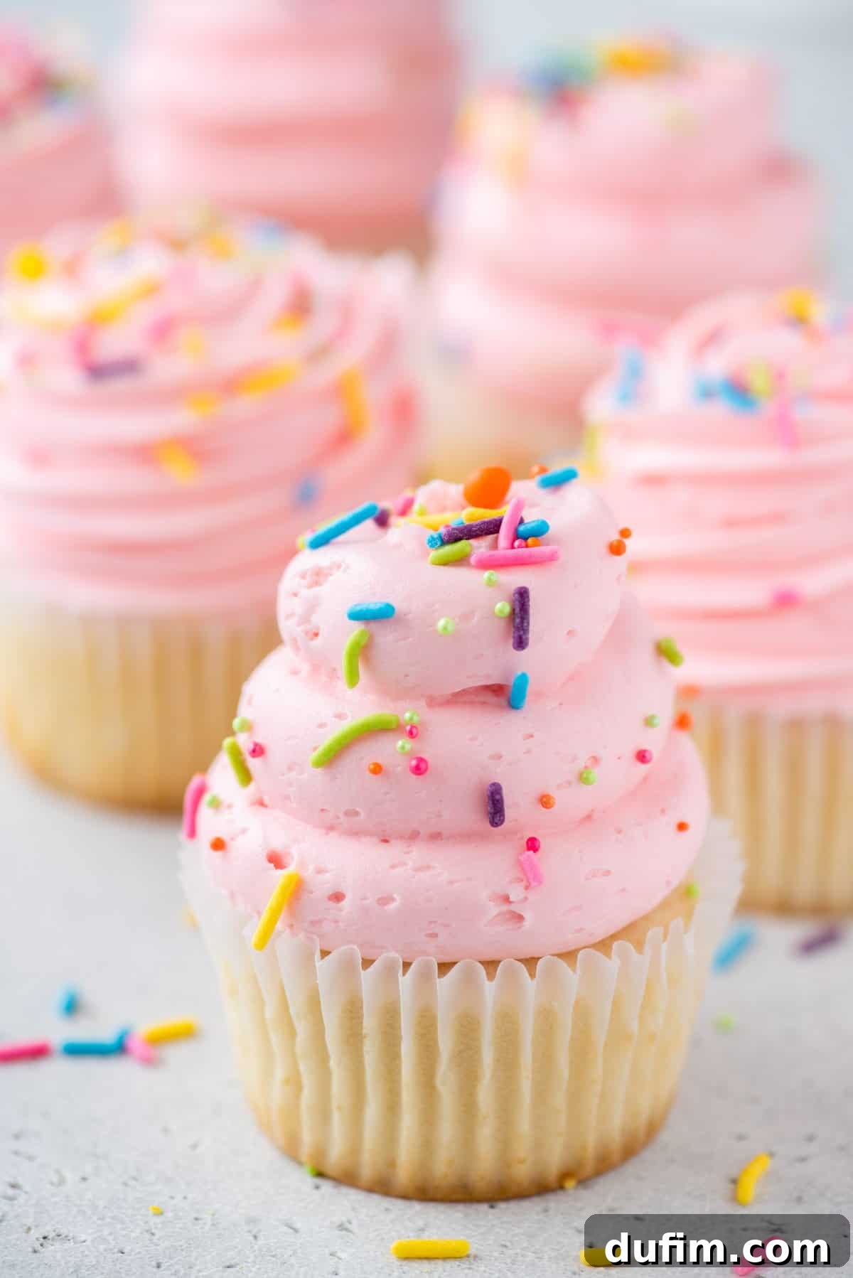 Delicious gluten-free vanilla cupcakes adorned with vibrant pink frosting and playful sprinkles, ready for any celebration.