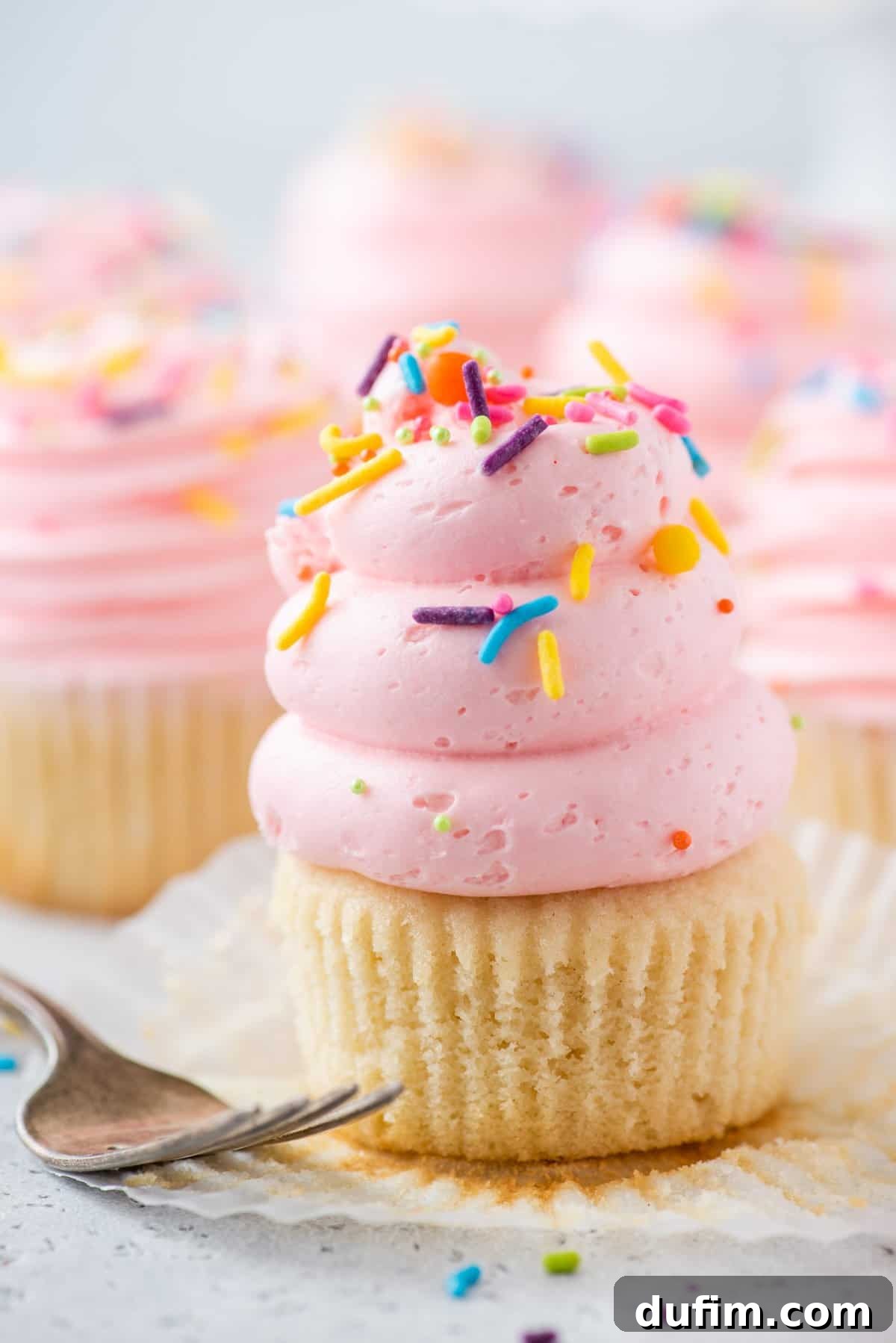 A delightful gluten-free cupcake crowned with beautiful pink vanilla buttercream and a shower of colorful sprinkles.