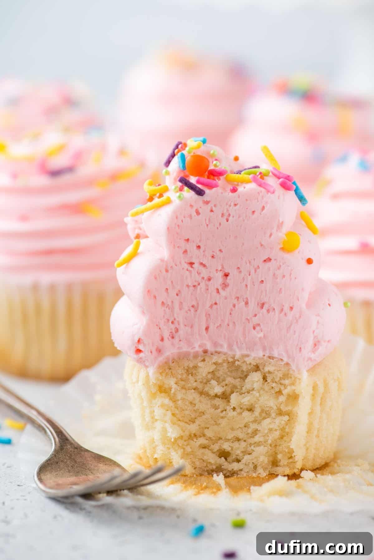 A delicious gluten-free cupcake with a bite taken out, showcasing its incredibly fluffy and moist texture within.