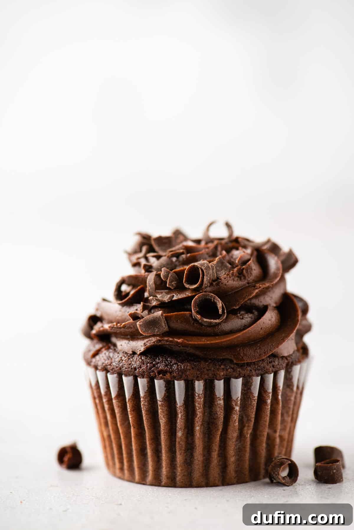 Experience the ultimate gluten-free chocolate cupcakes: moist crumb, decadent frosting, and classic flavor that rivals any traditional recipe. Closeup of a perfectly frosted gluten-free chocolate cupcake adorned with delicate chocolate curls, highlighting its moist texture and rich appearance.