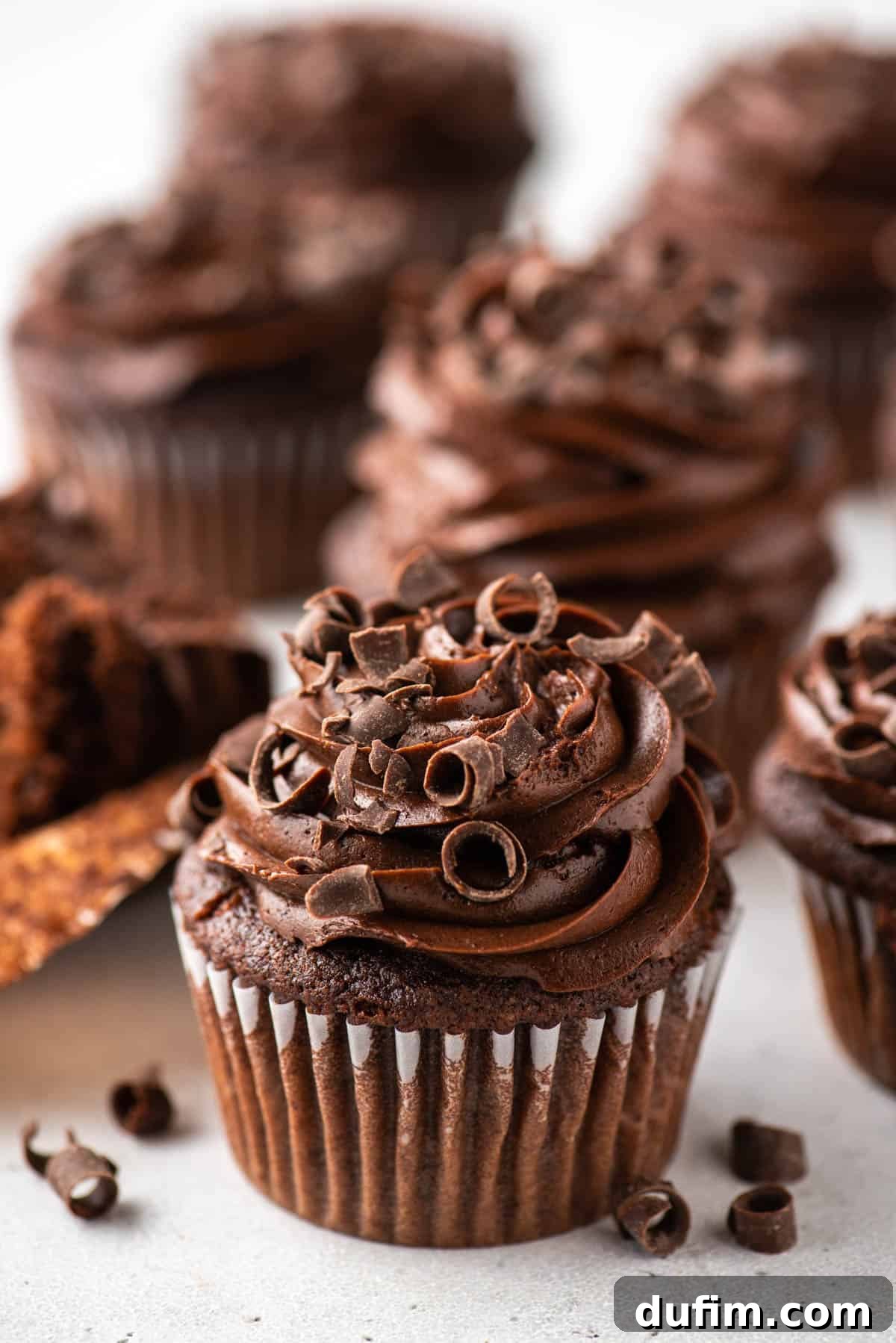 Indulge in these magnificent gluten-free chocolate cupcakes, featuring a moist crumb and decadent frosting that captures the essence of classic baking. A tray of beautifully frosted gluten-free chocolate cupcakes, each decorated with delicate chocolate curls, ready to be enjoyed.
