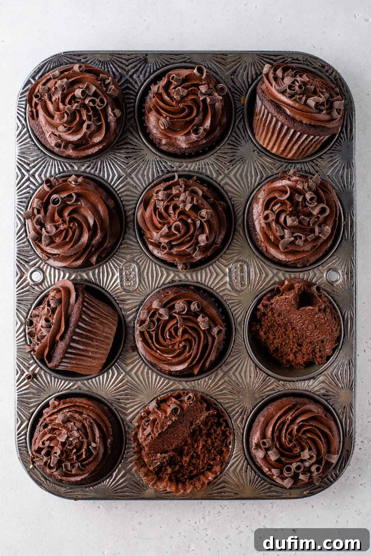 A feast for the eyes: perfectly frosted gluten-free chocolate cupcakes, demonstrating a moist crumb and truly decadent frosting. Rows of beautifully frosted gluten-free chocolate cupcakes, still in their muffin tin, each topped with a generous swirl of chocolate frosting.