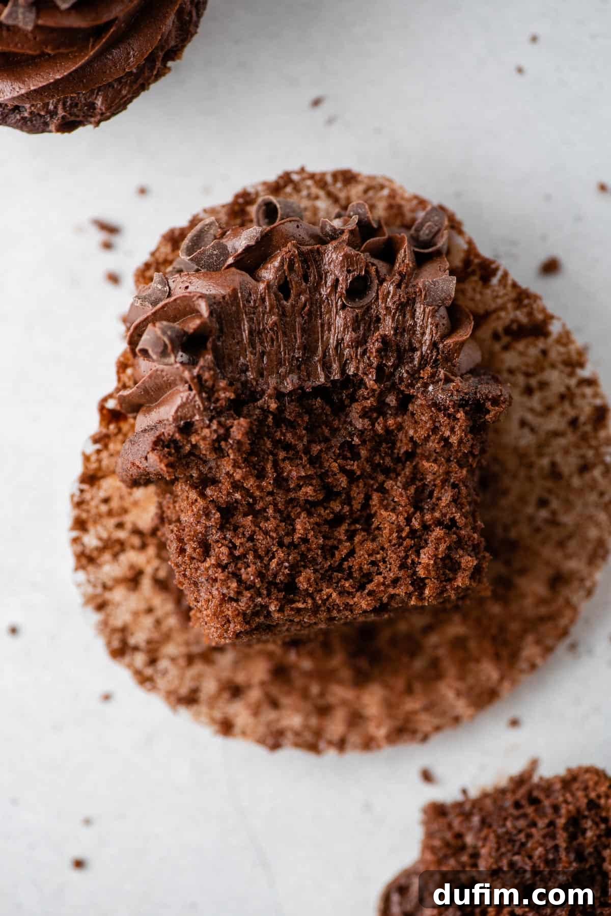 A perfect gluten-free chocolate cupcake: revealing a moist, tender cake that is every bit as good as the classic, even with a bite taken out. A close-up view of a gluten-free chocolate cupcake with a bite taken out, revealing its soft, tender, and moist interior cake crumb.