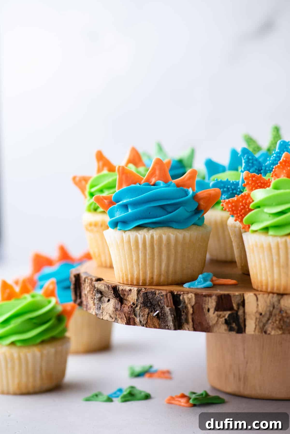 Dinosaur cupcakes on rustic log cake stand
