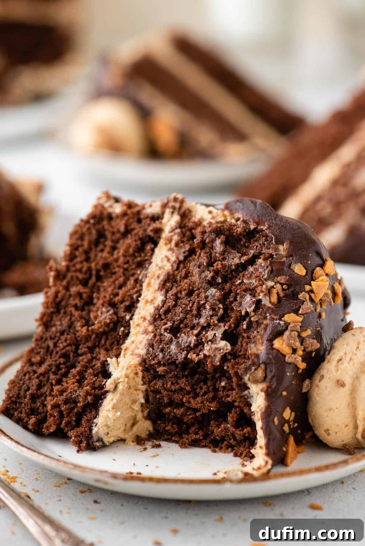 A close-up shot of a slice of Butterfinger cake on a plate, with a fork removing a bite, highlighting the texture and layers of the dessert.