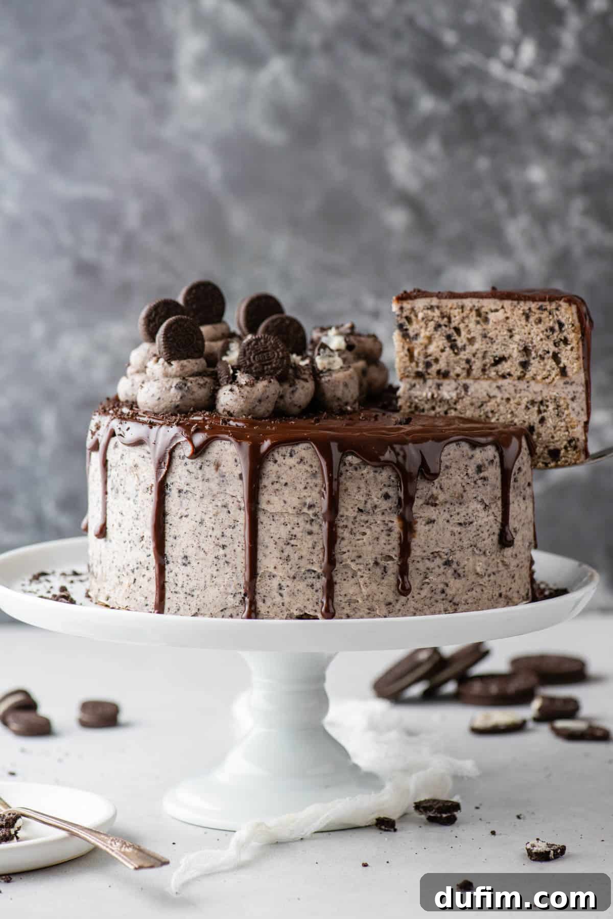 A whole Oreo cake on a cake stand, with a slice perfectly removed, revealing the delicious layers inside.
