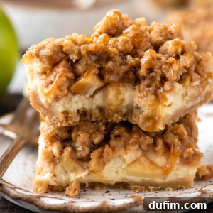Closeup of stacked caramel apple cheesecake bars with a bite taken out of the top bar, emphasizing the inviting layers.