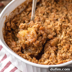 Spoon scooping caramel apple crisp from dish