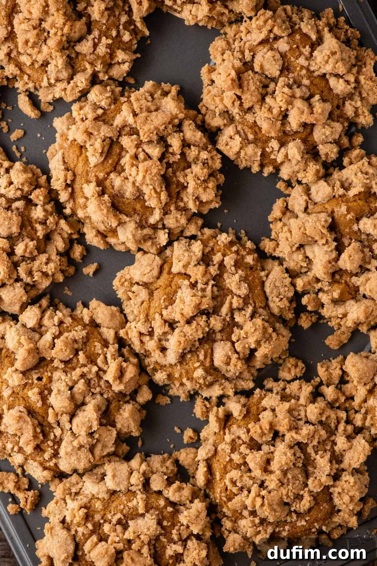 Autumn Spiced Gluten-Free Pumpkin Streusel Muffins 2 gluten free pumpkin muffins topped with streusel lined up in a muffin pan