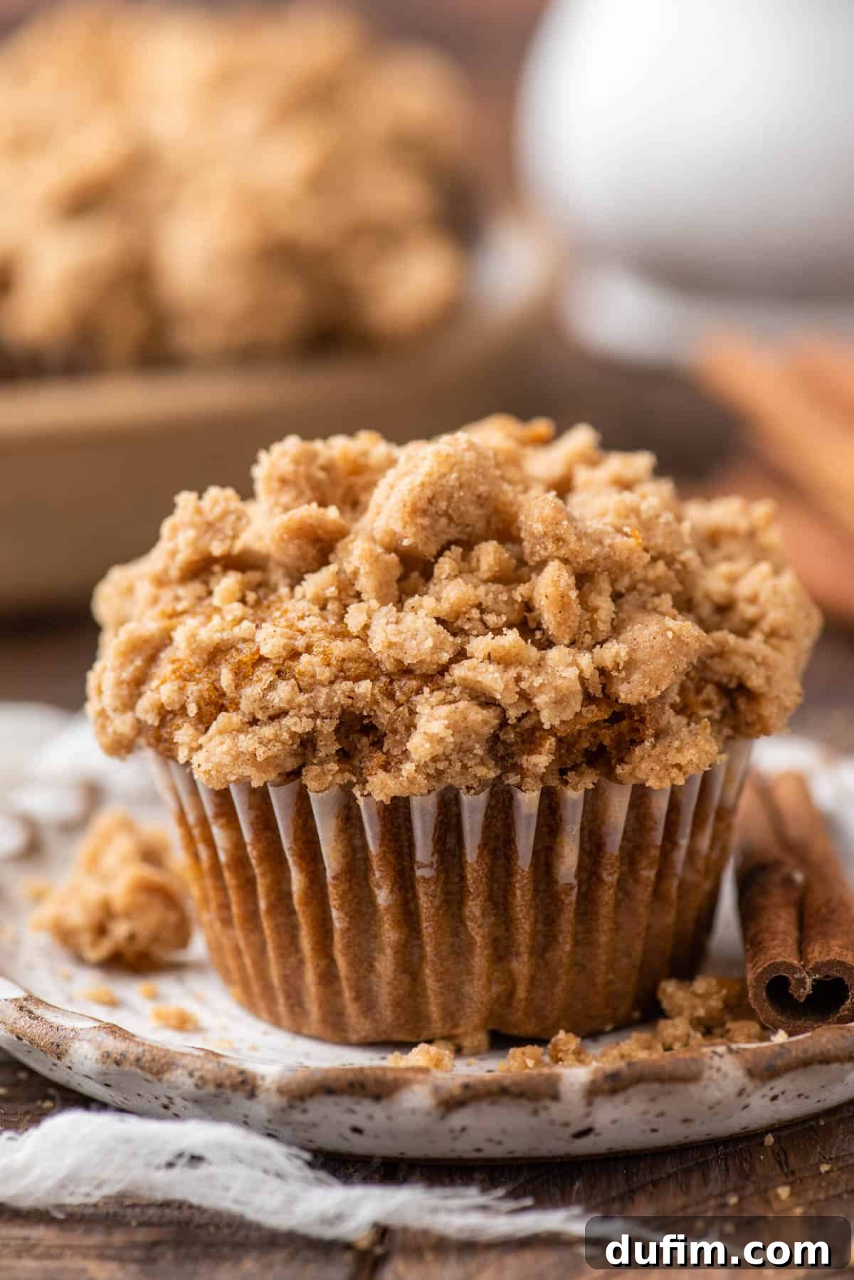 Autumn Spiced Gluten-Free Pumpkin Streusel Muffins 11 single pumpkin muffin with crumb topping on speckled ceramic plate on brown background