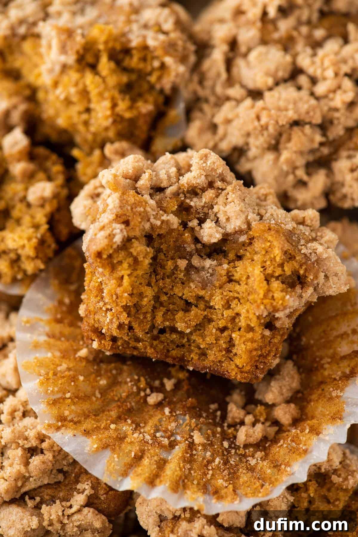 Autumn Spiced Gluten-Free Pumpkin Streusel Muffins 3 a single pumpkin muffin with streusel topping with bite taken out of it