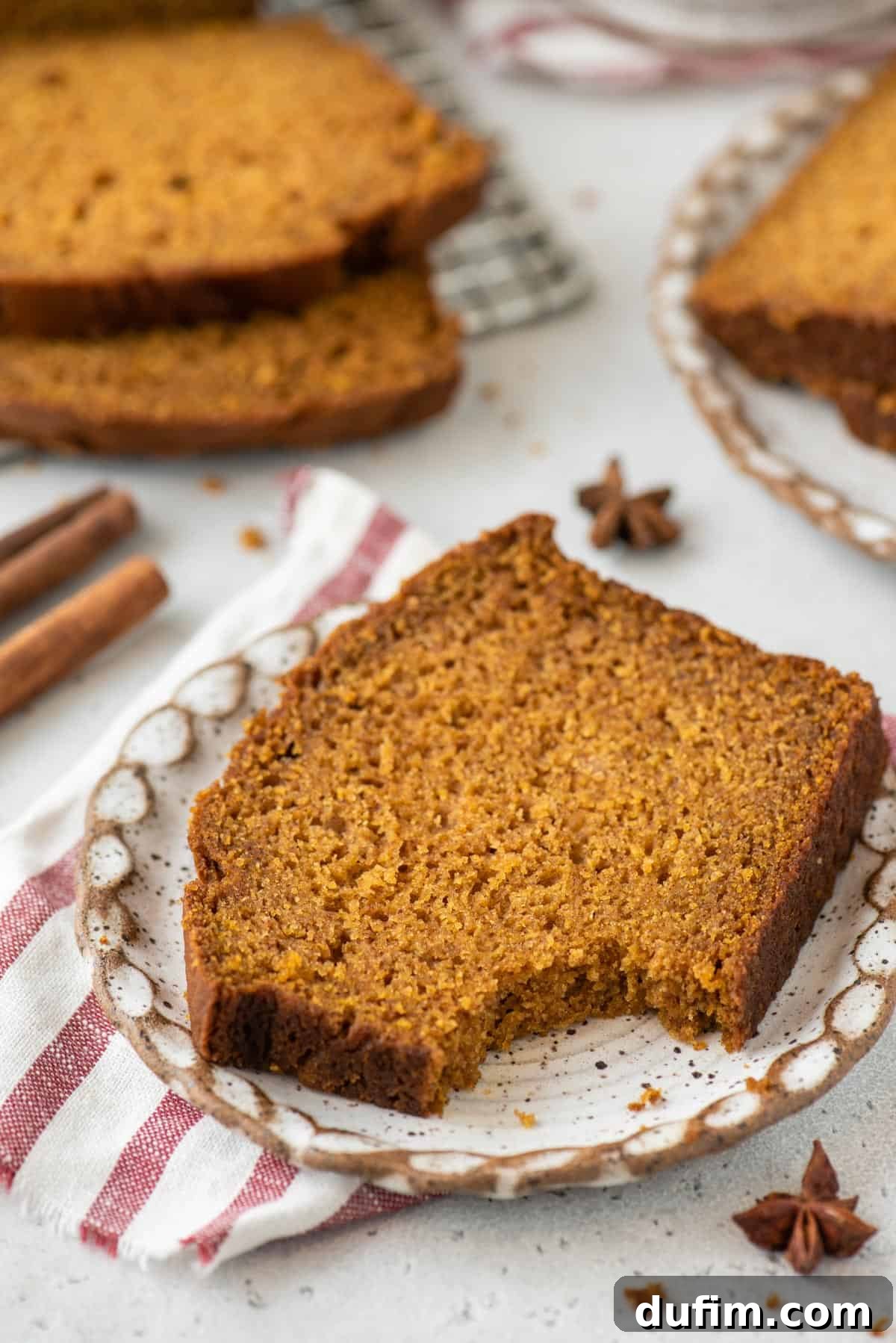 A slice of gluten-free pumpkin bread with a bite gone sits on a small plate.
