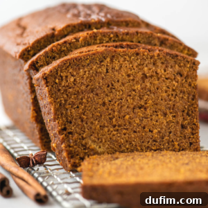 A sliced loaf of gluten-free pumpkin bread on a cooling rack.