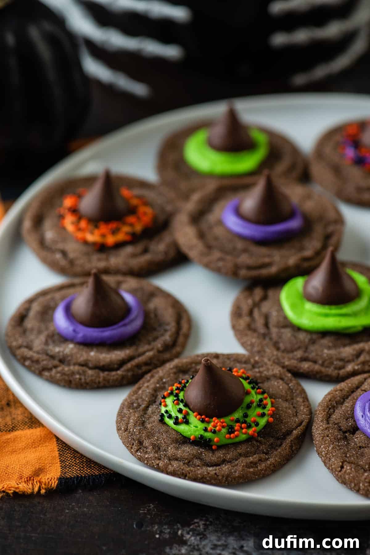 A charming plate overflowing with Witch Hat Cookies, decorated with purple, orange, and green frosting, and festive Halloween sprinkles.