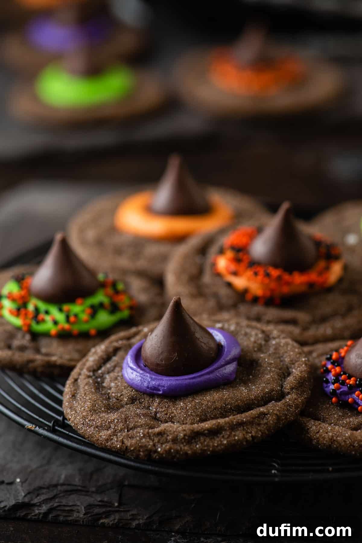 A close-up shot highlighting the intricate details of a Witch Hat Cookie, with vibrant frosting and festive sprinkles surrounding the chocolate Kiss.
