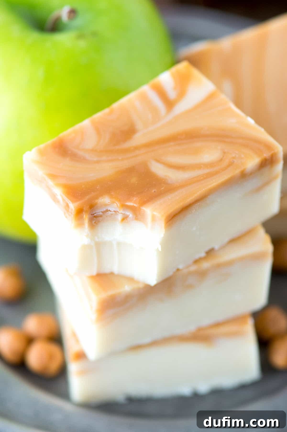 Stacked slices of caramel apple fudge, with a bite removed from the top piece, highlighting its inviting texture.