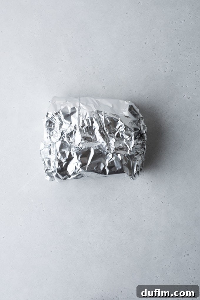 The chocolate fudge, now completely wrapped in aluminum foil, forming a protective seal for freezing.