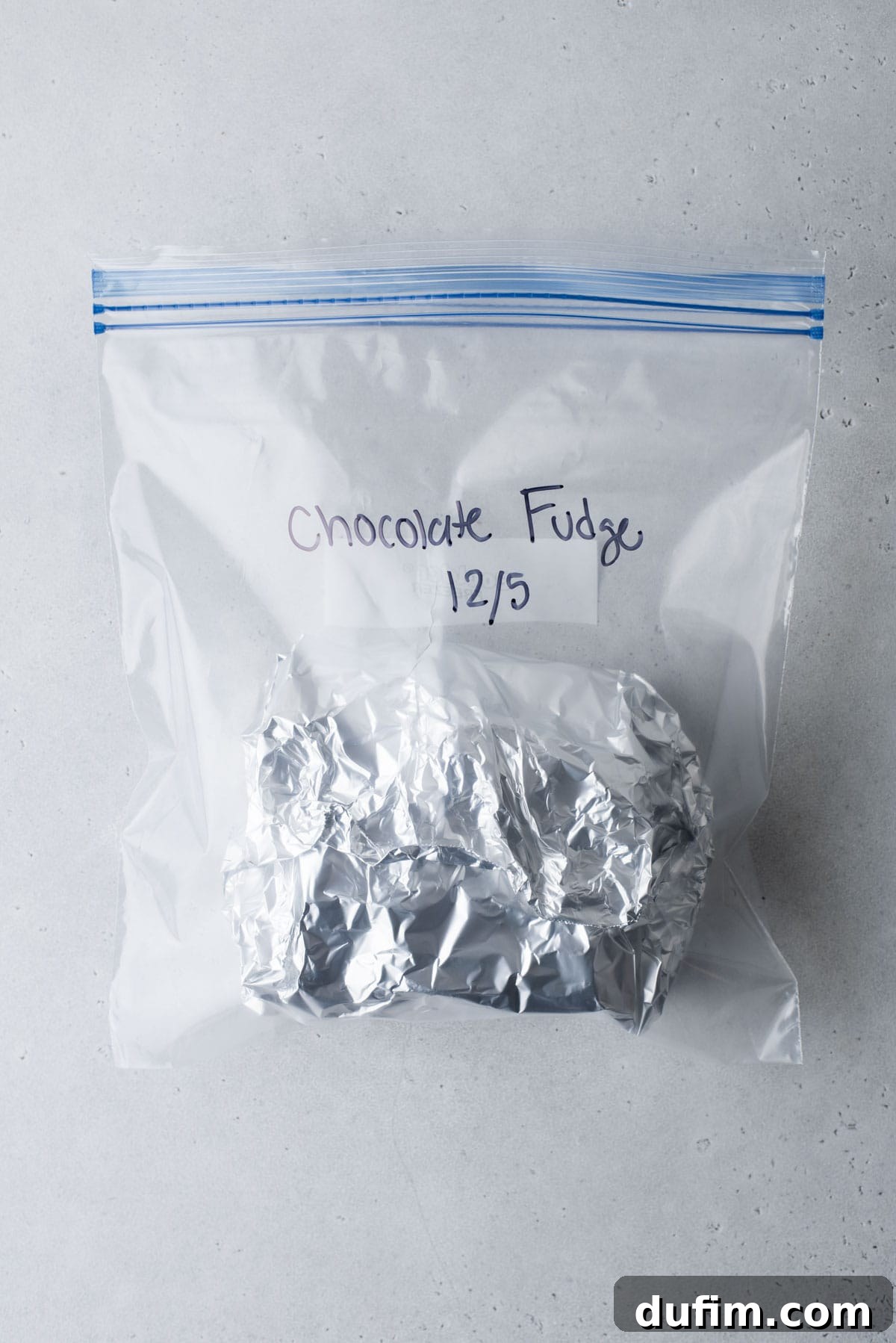 A securely wrapped bundle of chocolate fudge, prepared for the freezer, is placed inside a clear freezer bag.