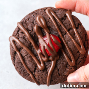 A hand holding a chocolate covered cherry cookie, showcasing its rich appearance and perfect drizzle.