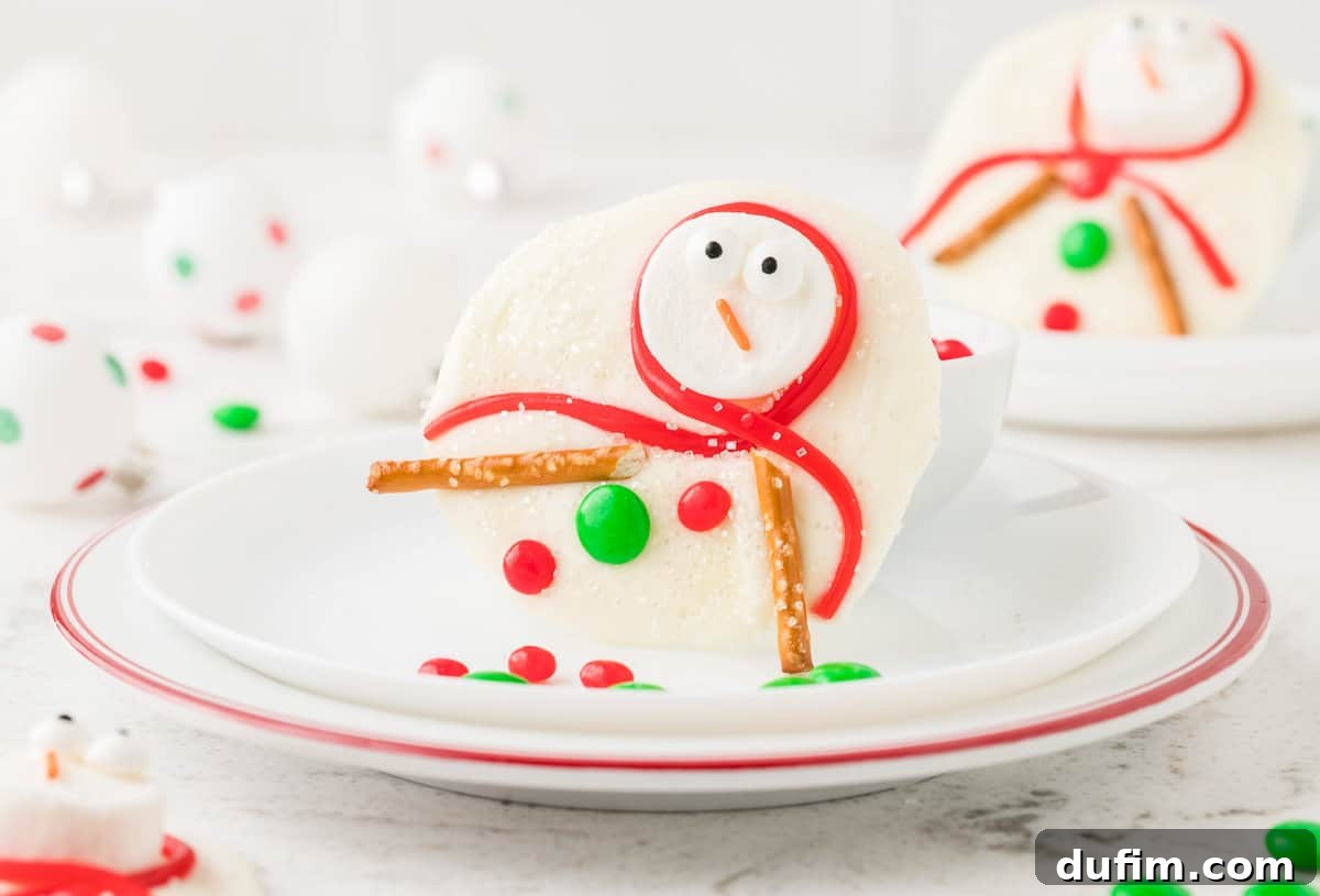 A charming piece of melted snowman bark, featuring a marshmallow snowman with candy eyes, an orange jimmy nose, a red Twizzler scarf, pretzel arms, and candy buttons, propped elegantly on a white plate.