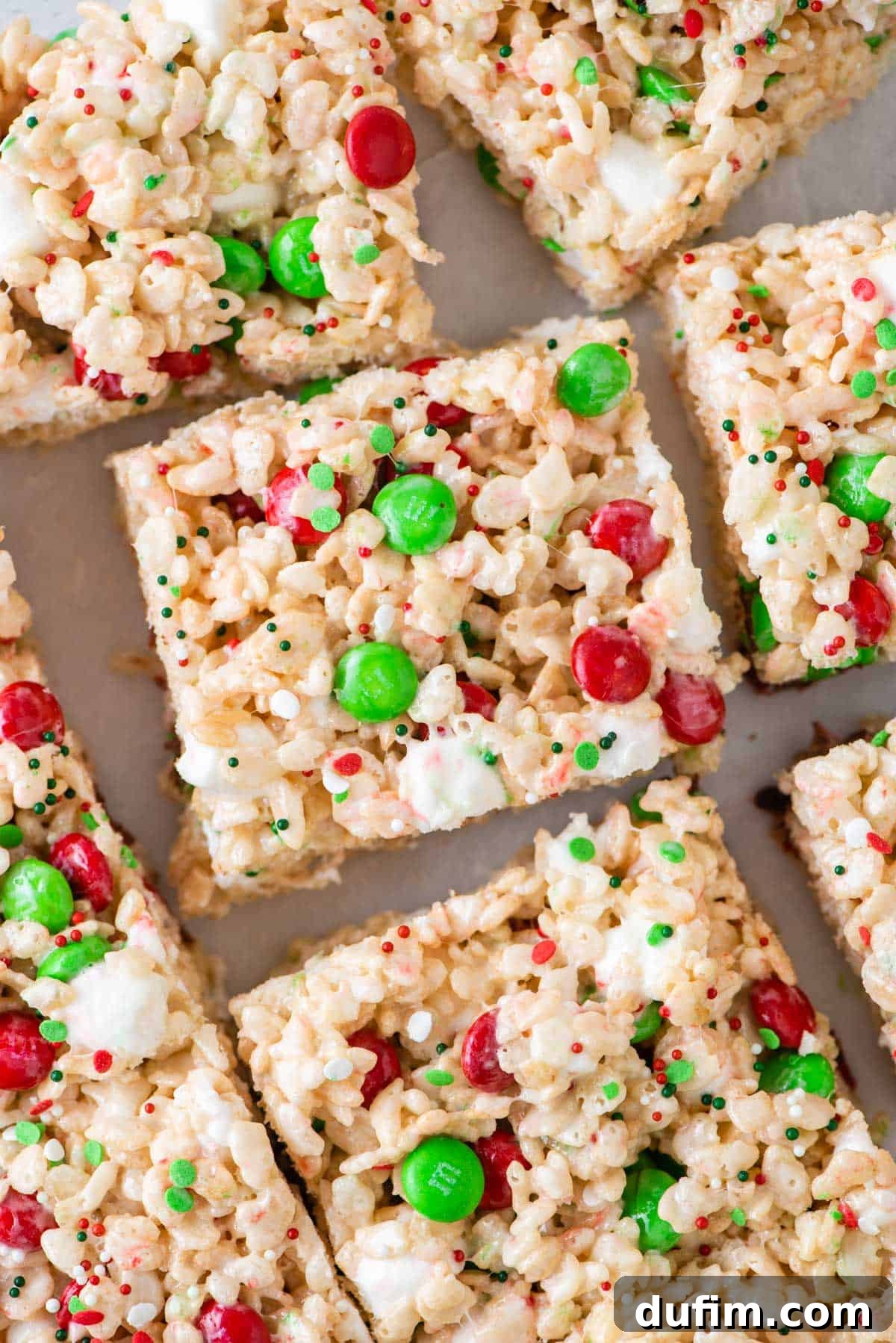 Overhead view of vibrant Christmas Rice Krispie treats decorated with red and green M&Ms and sprinkles, a perfect no-bake holiday dessert.