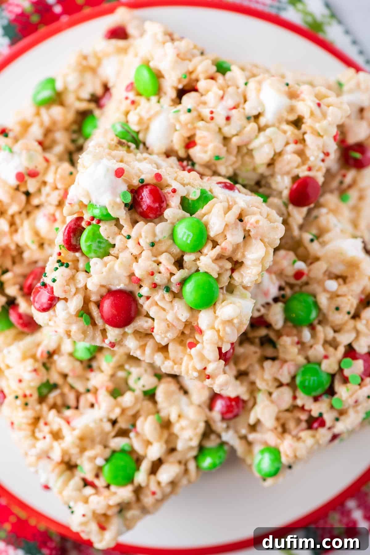 A perfectly stacked pile of freshly made holiday Rice Krispie treats, glistening with marshmallow and colorful candy.