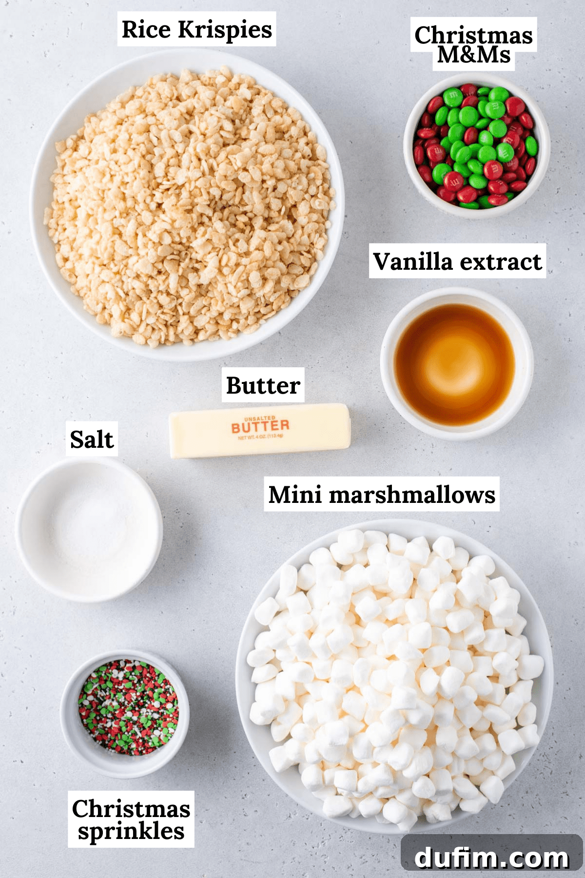Overhead flat lay of individual ingredients for Christmas Rice Krispie treats, neatly measured out in bowls.