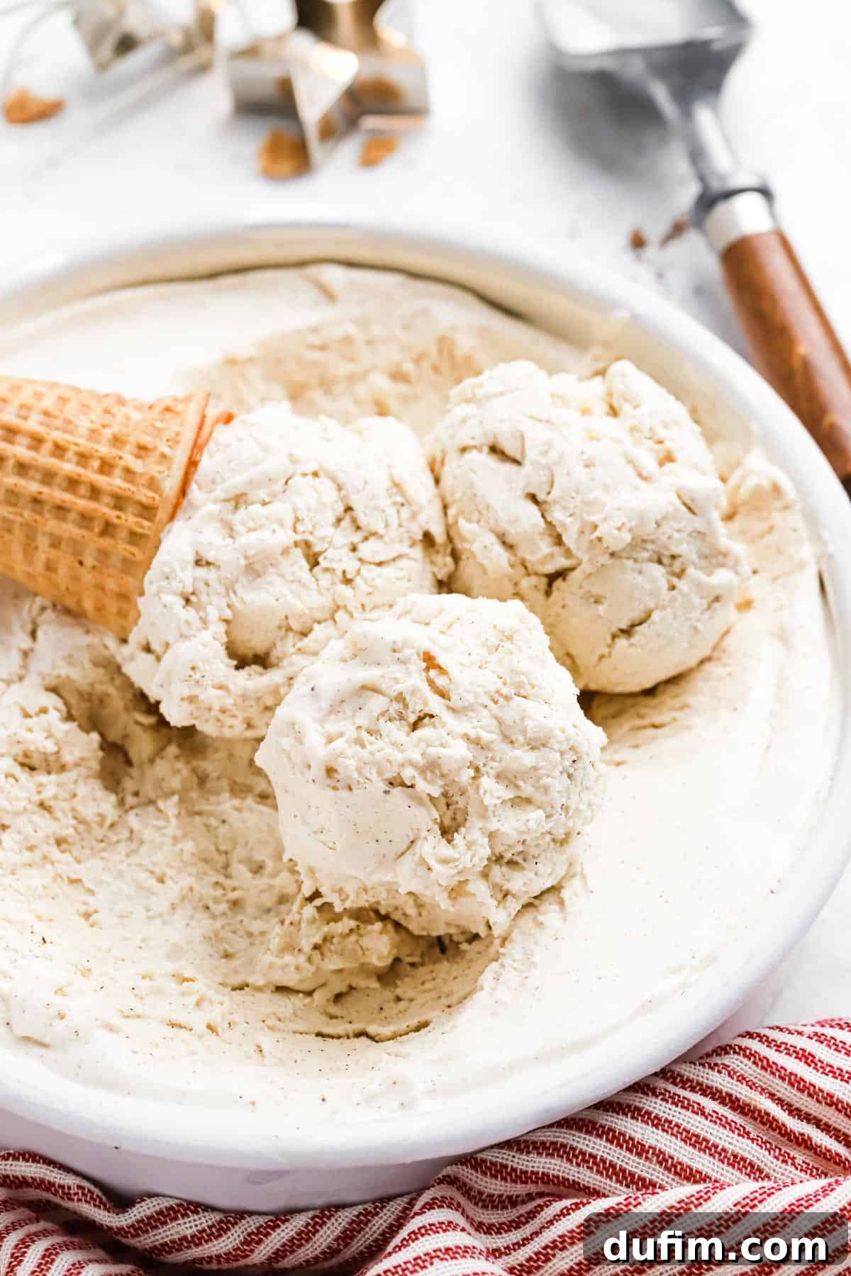 Made with only 6 ingredients, Eggnog Ice Cream is rich, creamy, and perfectly spiced. Perfect for the holidays, with 10 minutes of prep! Three scoops of rich, creamy eggnog ice cream in a bowl with a waffle cone resting on the side, ready to be enjoyed as a festive holiday treat.