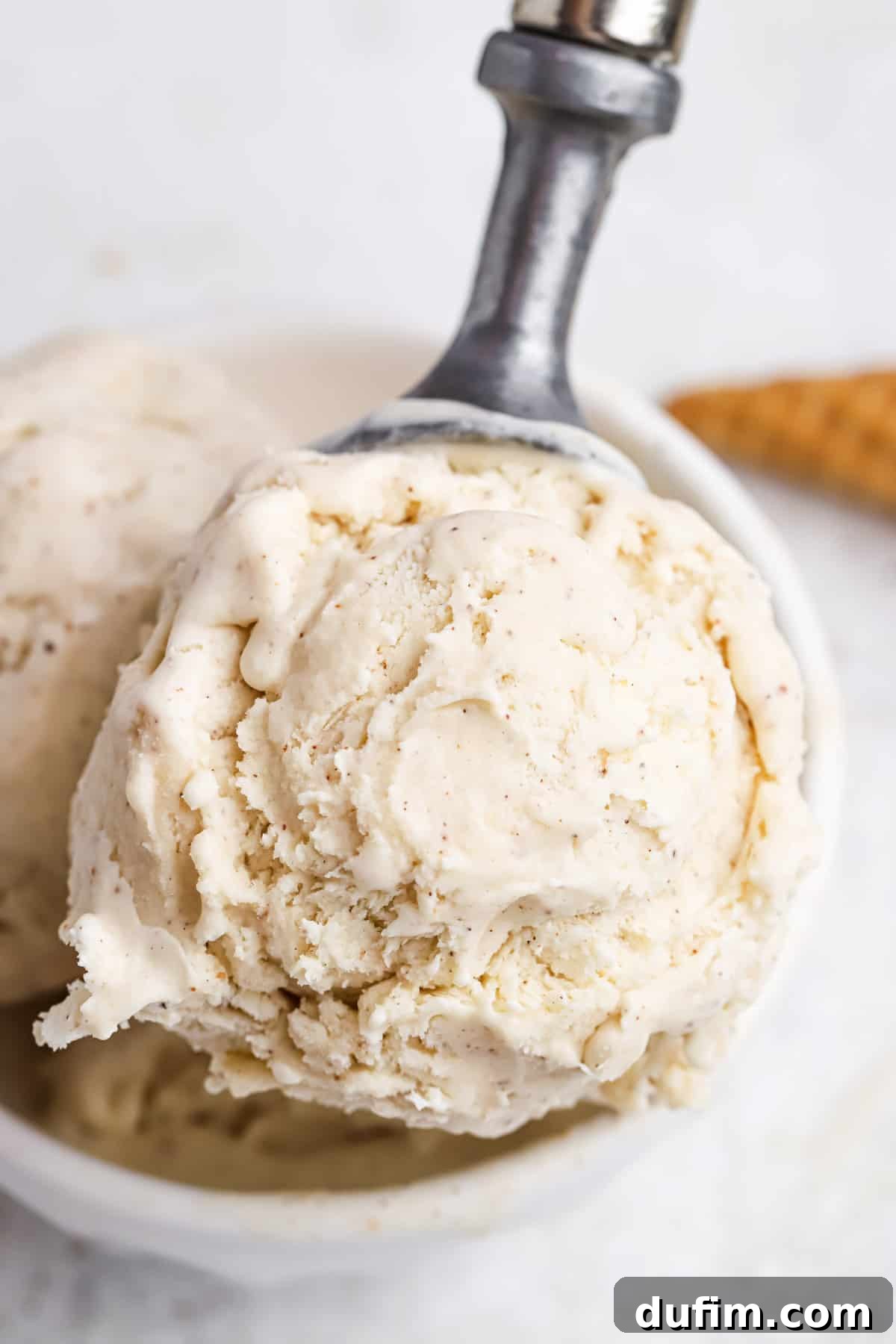 Made with only 6 ingredients, Eggnog Ice Cream is rich, creamy, and perfectly spiced. Perfect for the holidays, with 10 minutes of prep! A close-up shot of a perfectly scooped ball of eggnog ice cream, showcasing its creamy texture and the subtle speckles of nutmeg.