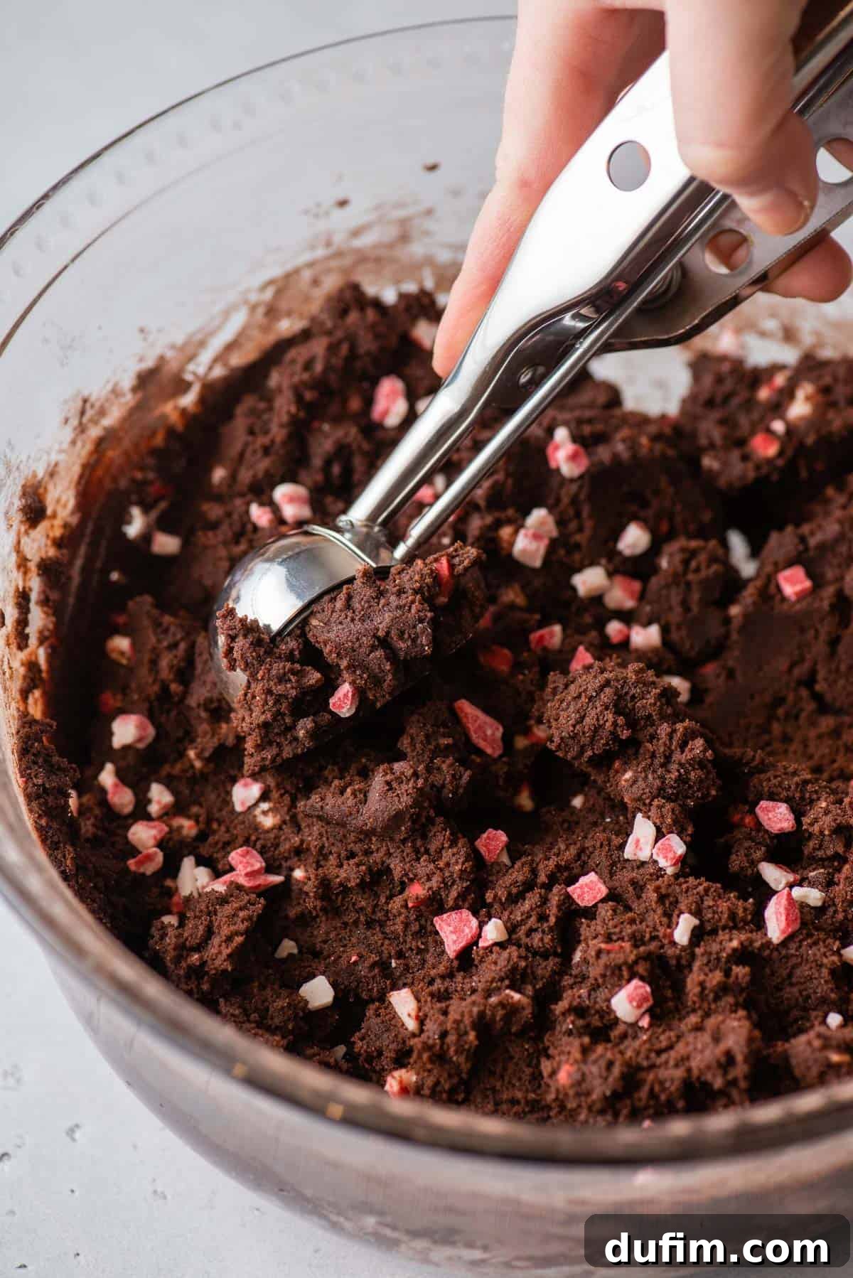 Portioning Chocolate Peppermint Cookie Dough with a Scoop. A cookie scoop gathering chocolate cookie dough, illustrating the portioning process.