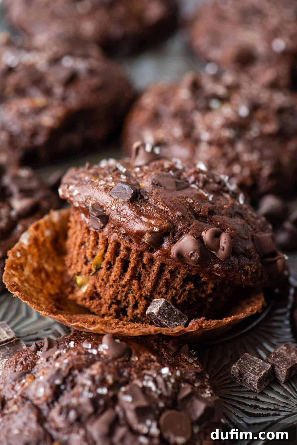 These Chocolate Zucchini Muffins are rich, moist, and oh-so-good. The zucchini adds moisture while cocoa powder adds chocolate decadence. A single chocolate zucchini muffin still in its paper liner, highlighting its height and bakery-style appearance.