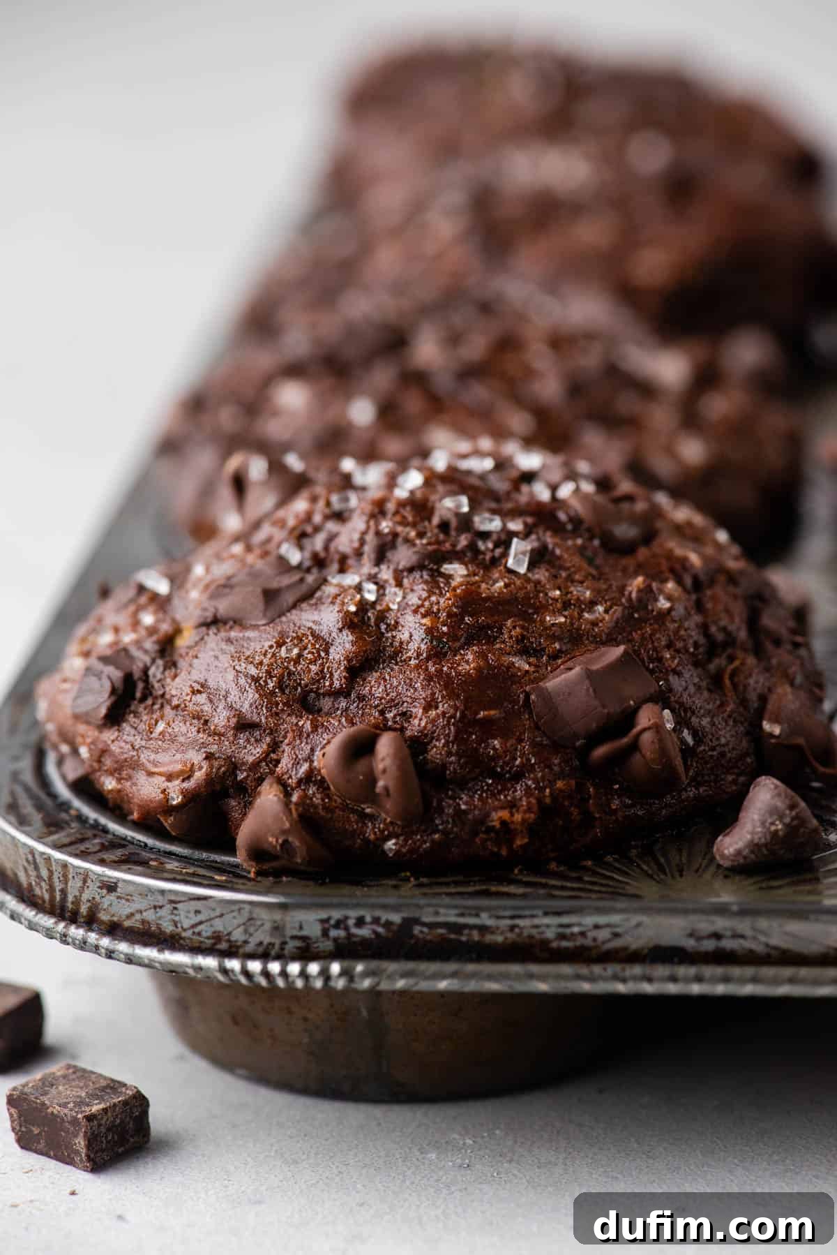 These Chocolate Zucchini Muffins are rich, moist, and oh-so-good. The zucchini adds moisture while cocoa powder adds chocolate decadence. Chocolate zucchini muffins baking in a muffin pan, showing perfect spacing for optimal rise.