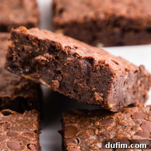 A top-down view of a single fudgy banana brownie, adorned with a dusting of powdered sugar, highlighting its rich, dark interior and visible chocolate chips, promising a delightful texture.