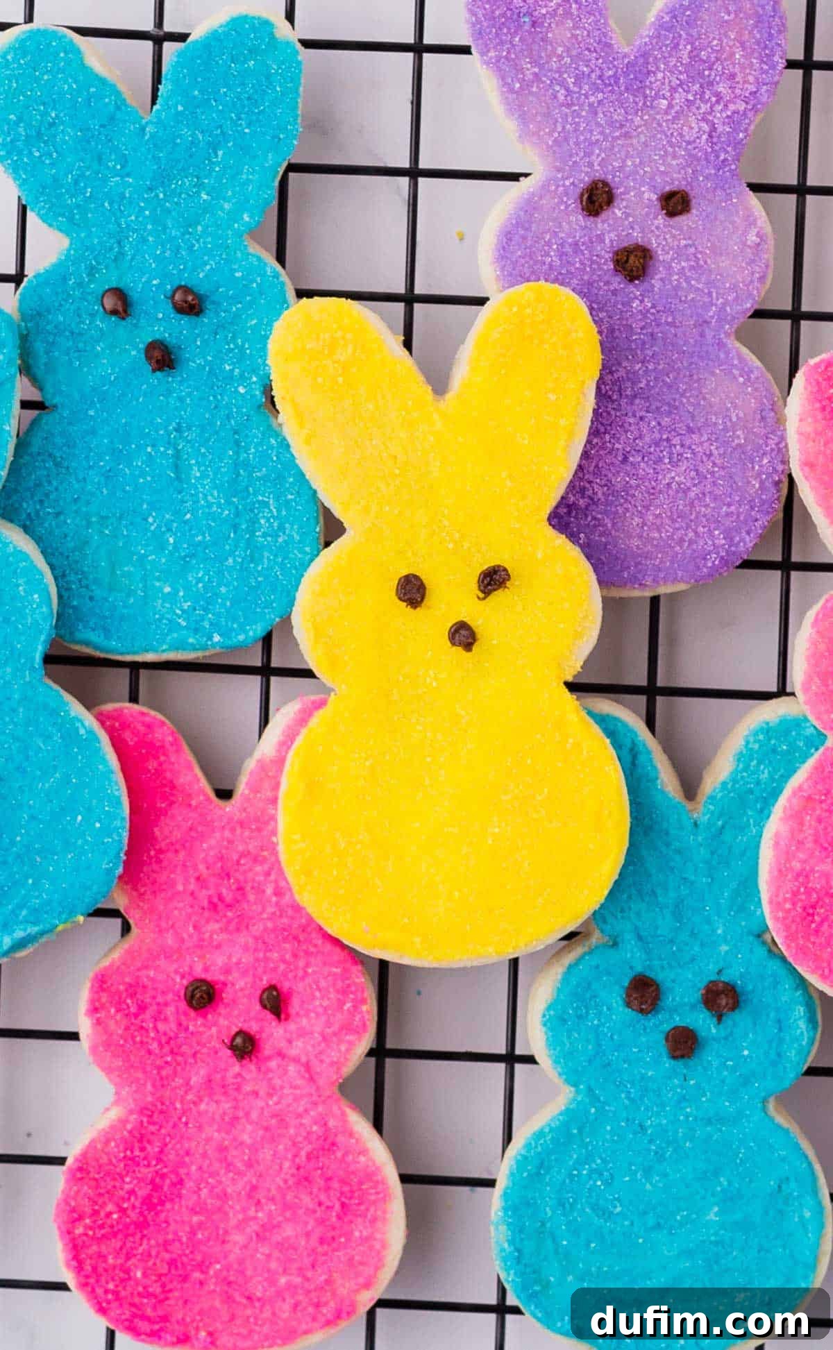 Festive Peeps Bunny Sugar Cookies 10 blue, pink, purple and yellow peeps bunny cookies stacked up on a cooling rack