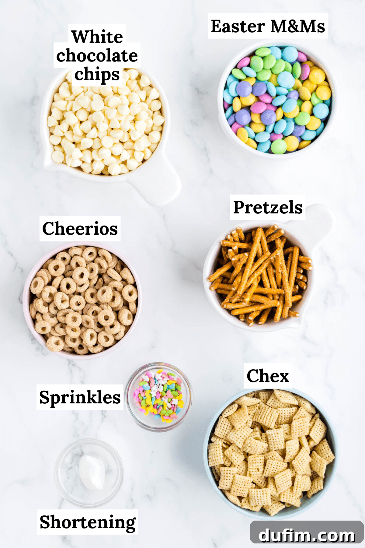 ingredients for bunny bait including rice chex cereal, honey nut cheerios, pretzel sticks, easter M&Ms, white chocolate chips, vegetable shortening, and easter sprinkles