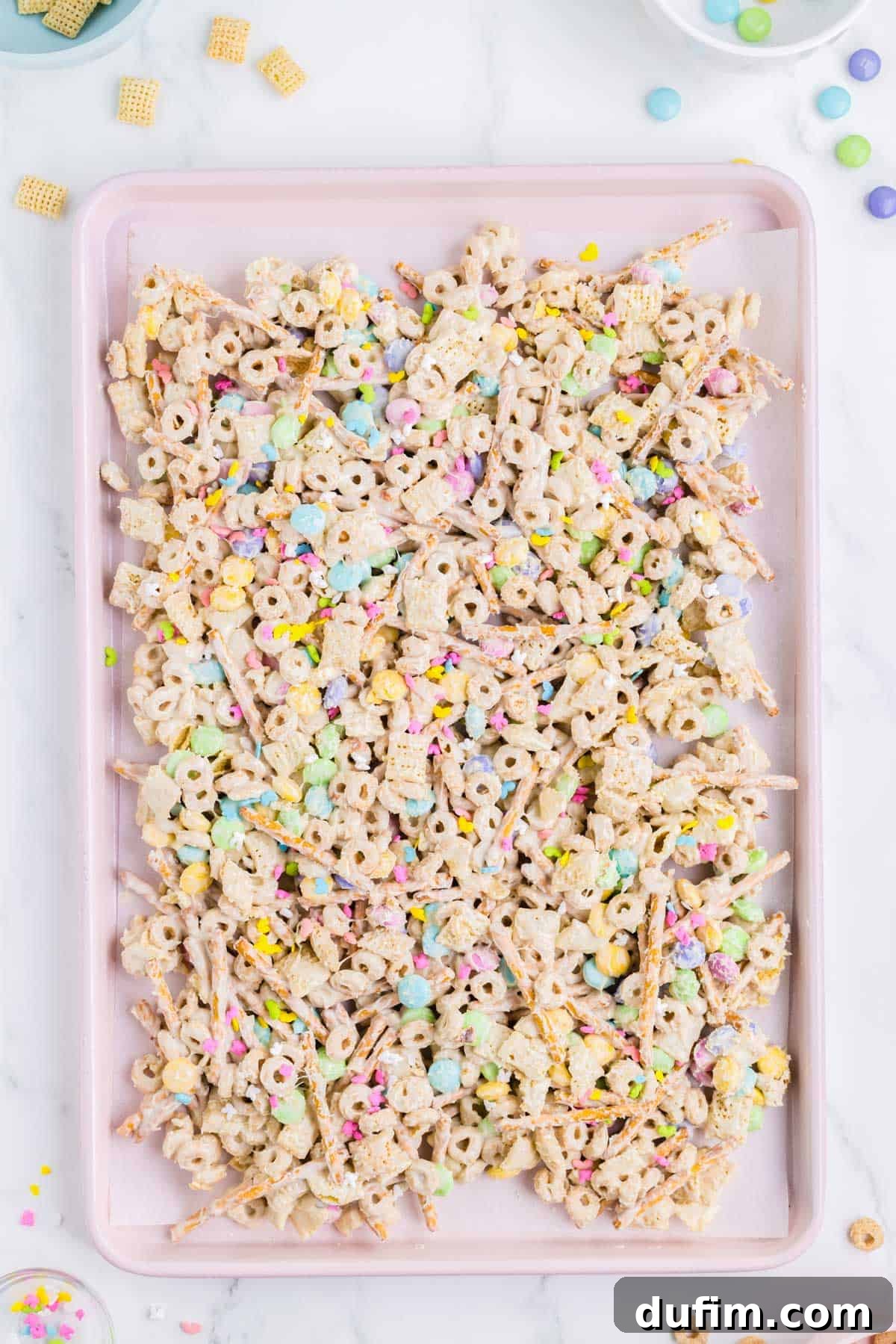 easter bunny bait snack mix spread out on a pink baking sheet