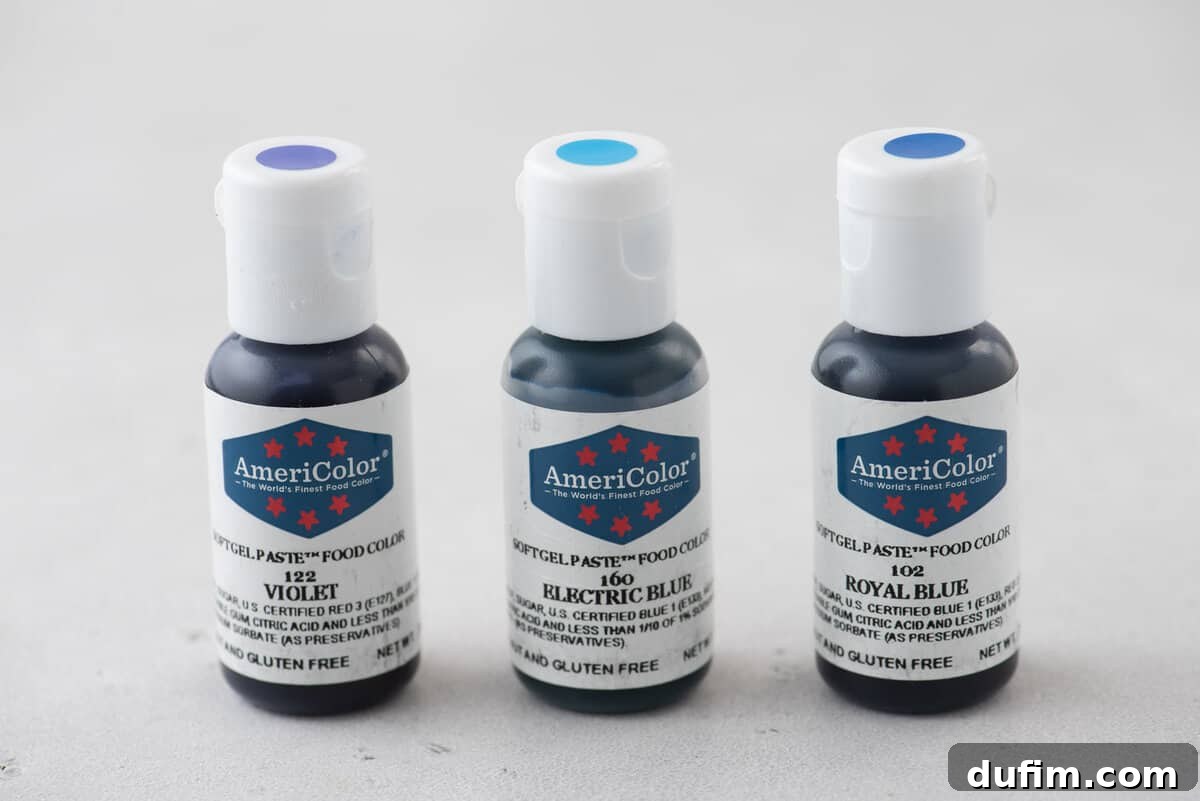 Three AmeriColor gel food coloring bottles arranged in a row: violet, electric blue, and royal blue, highlighting the essential colors for achieving the perfect Cookie Monster blue.