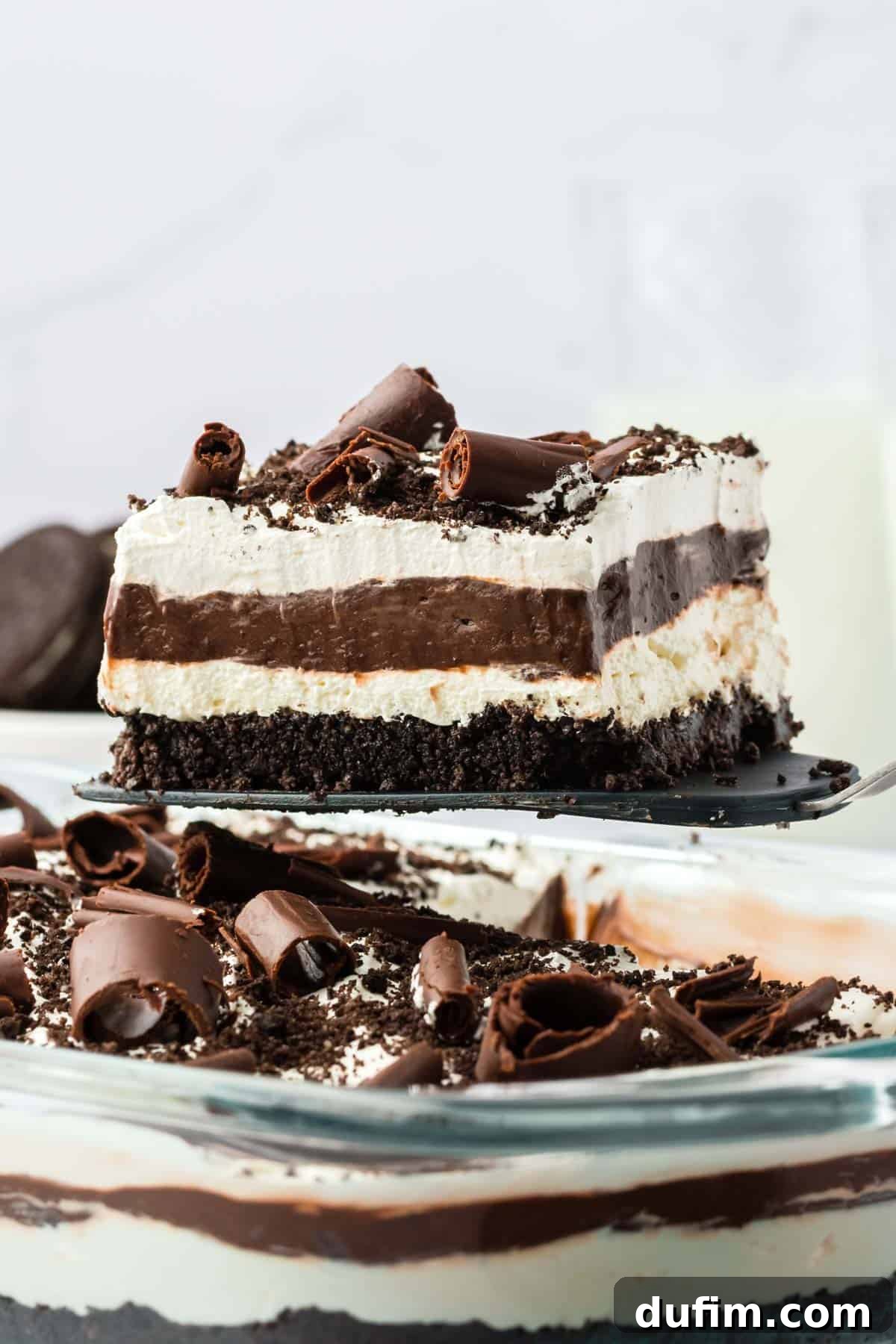 Ultimate Chocolate Lasagna Indulgence 3 A slice of chocolate lasagna being lifted out of a full dish with a spatula, clearly showing all the distinct layers from the side.