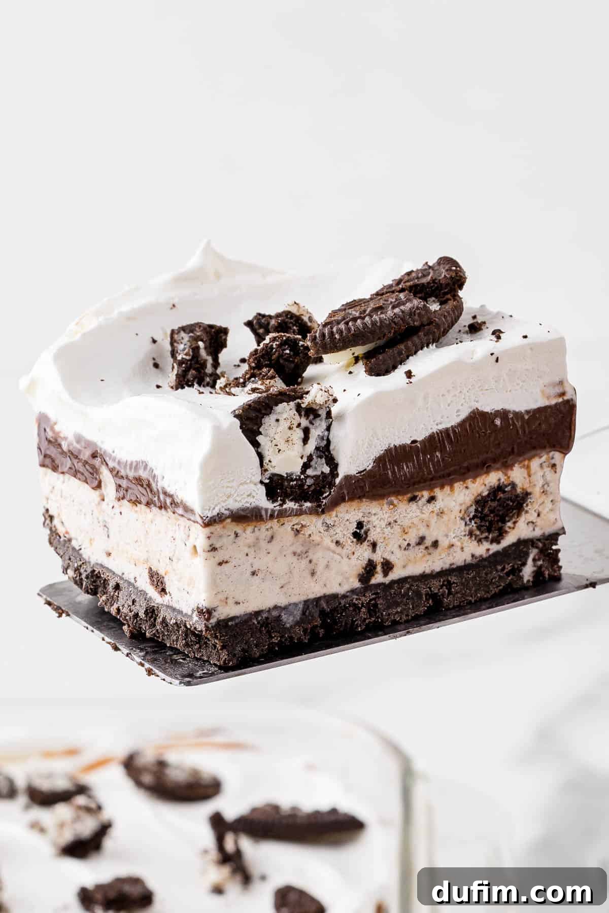 A pristine slice of Oreo ice cream cake being served, lifted from the dish with a spatula, ready to be enjoyed.