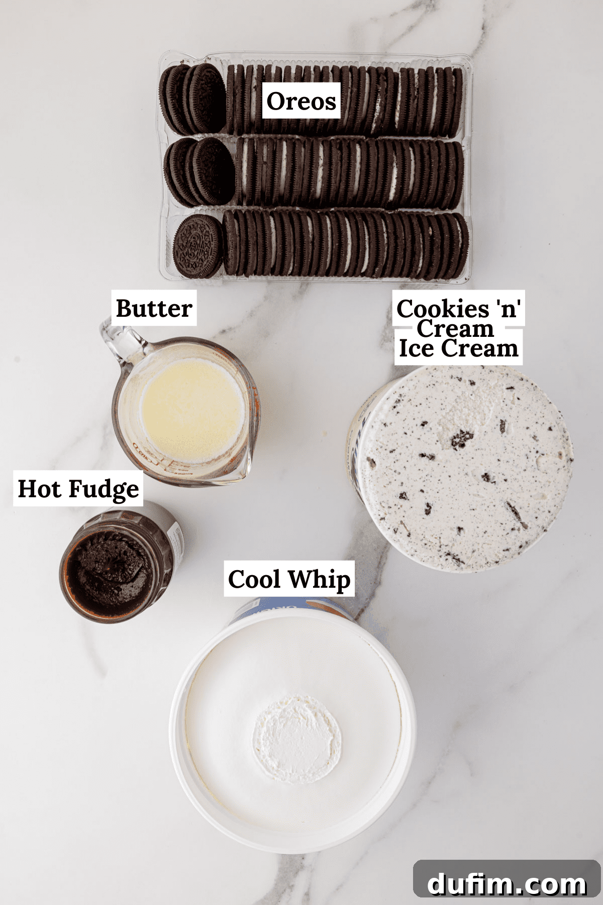 All the simple ingredients for Oreo ice cream cake laid out: a package of Oreos, a stick of butter, a jar of hot fudge, a tub of cool whip, and a half-gallon of cookies and cream ice cream.