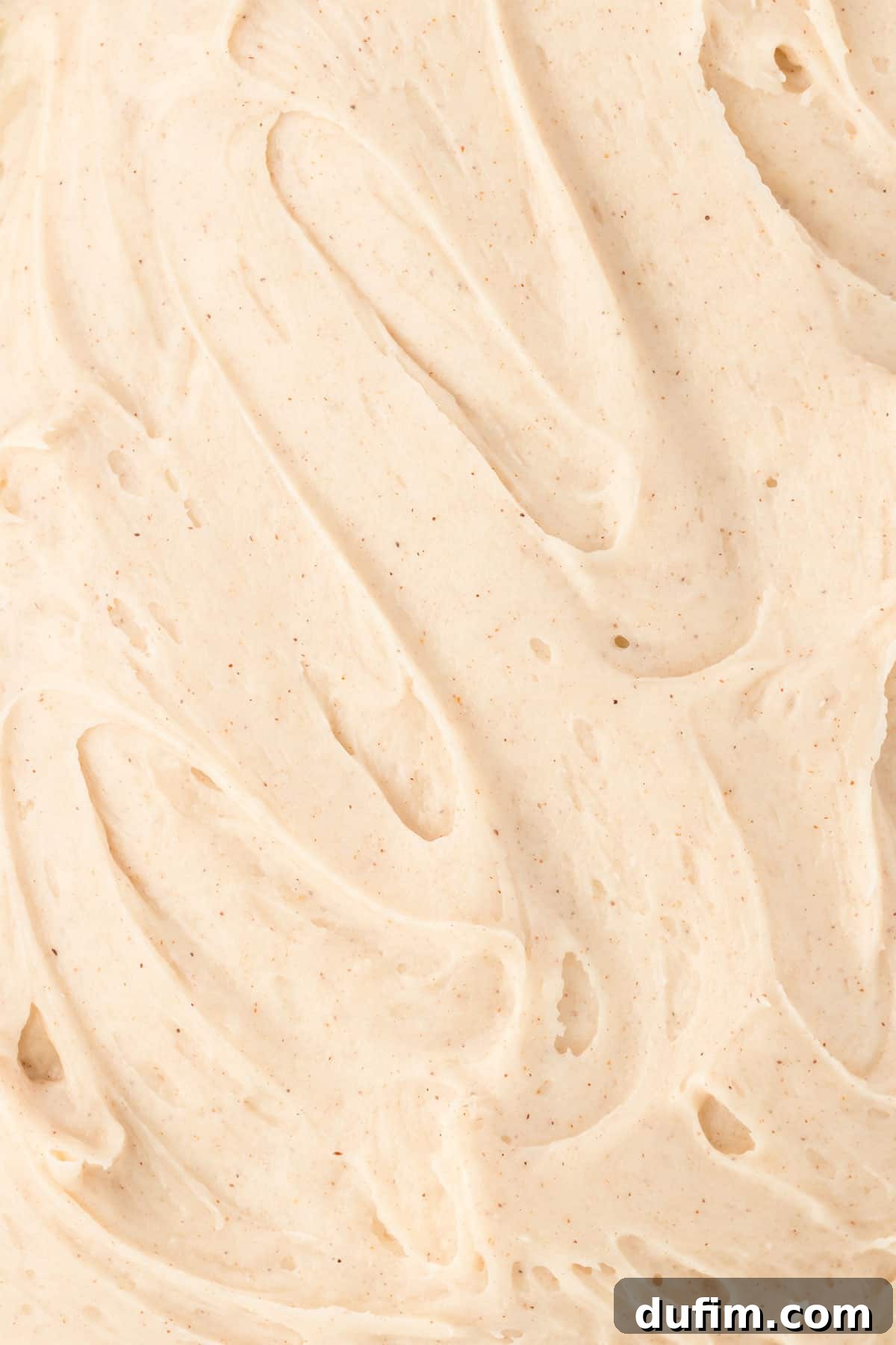 Dreamy Cinnamon Cream Cheese Frosting 8 A close-up view of cinnamon cream cheese frosting spread evenly in a flat layer, highlighting its smooth, creamy texture and inviting appearance.