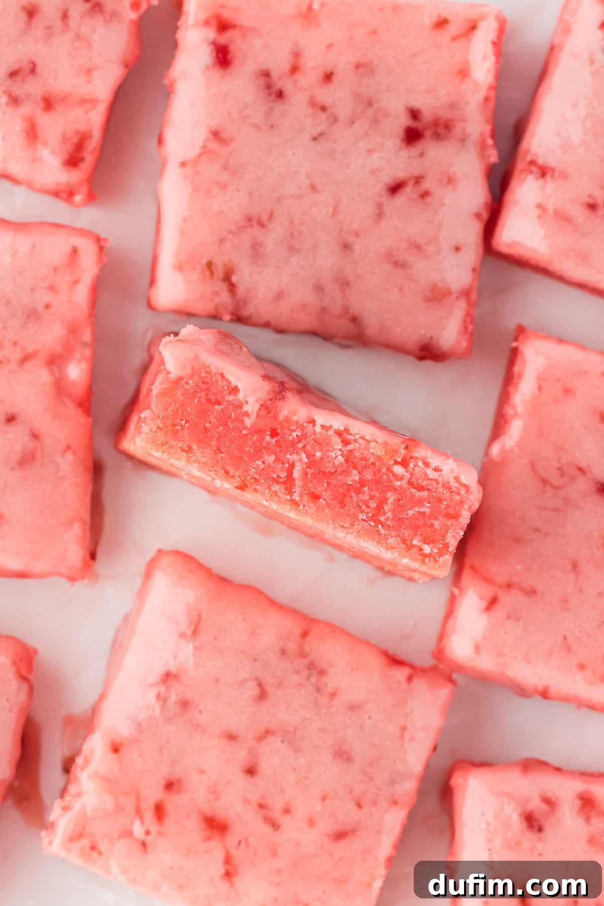 an arrangement of strawberry brownies on a white surface with the middle brownie on its side and the rest laying flat