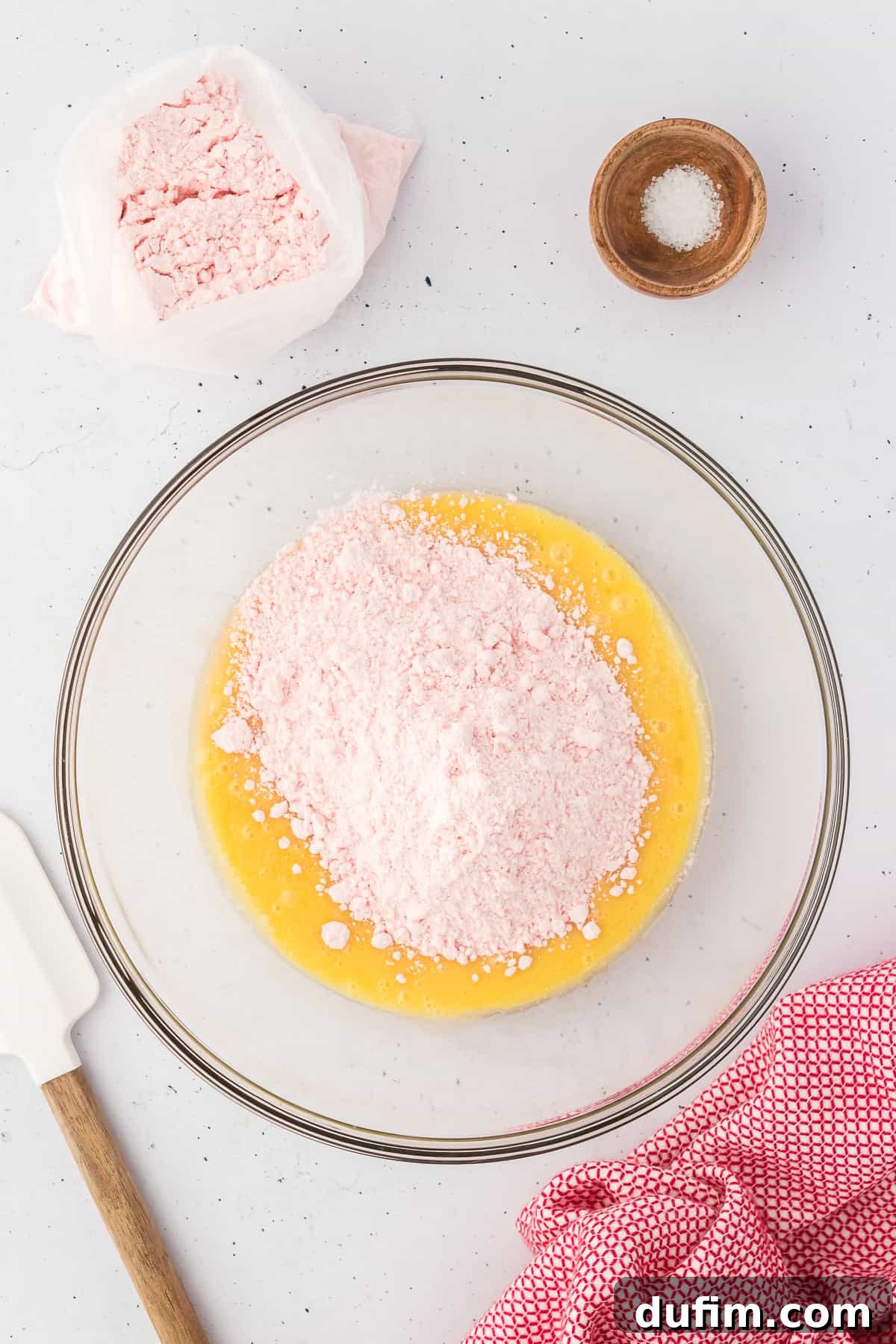 ingredients for strawberry brownies being mixed in a glass bowl