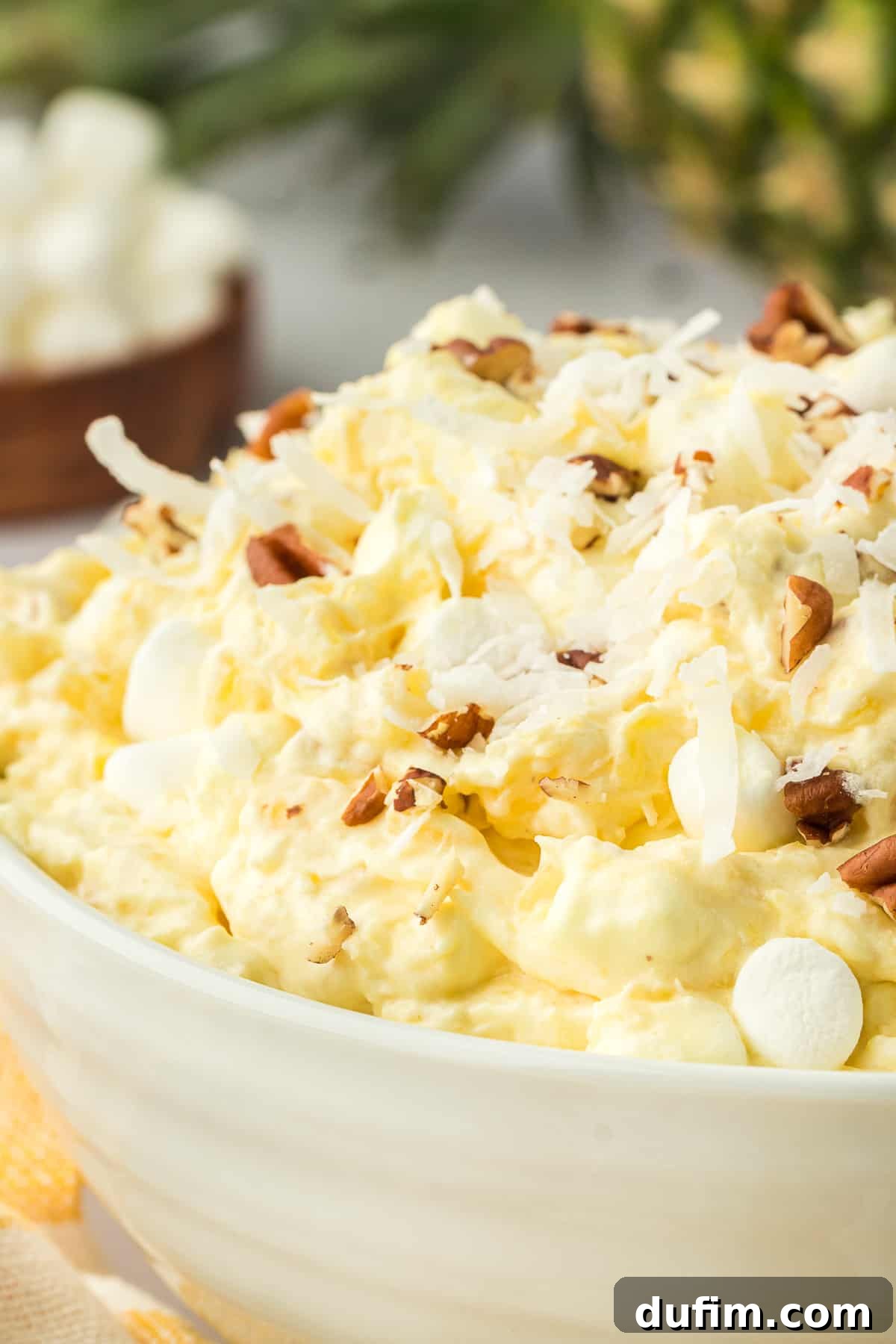 A close-up shot of a large, inviting bowl brimming with creamy pineapple fluff salad, ready to be served.